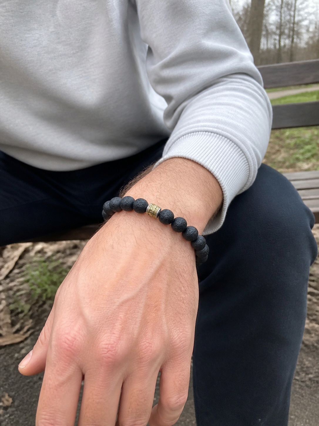 Western man wearing a carved black incense bead bracelet outdoors