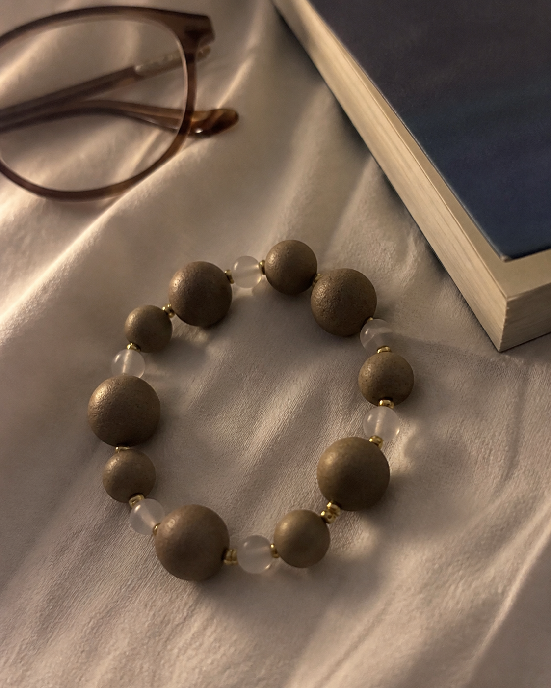 Mixed-size incense bead bracelet beside a bedside book