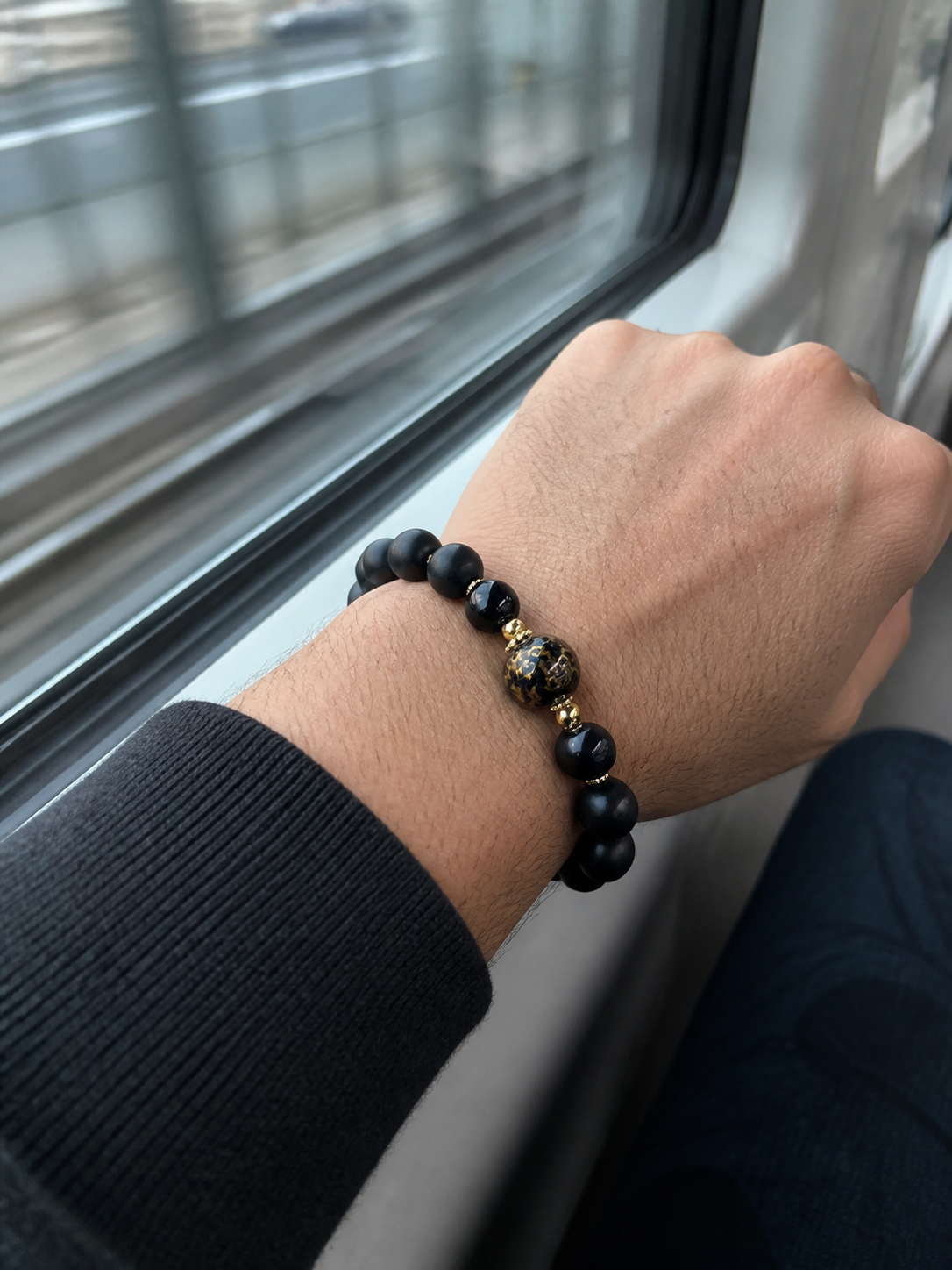 Western man wearing a black incense bead bracelet while commuting
