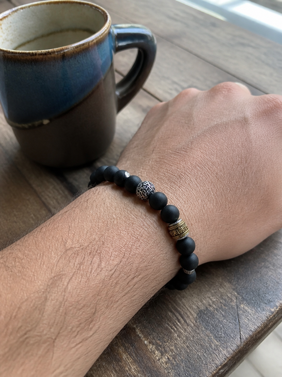 Man wearing a black incense bead bracelet at a cafe