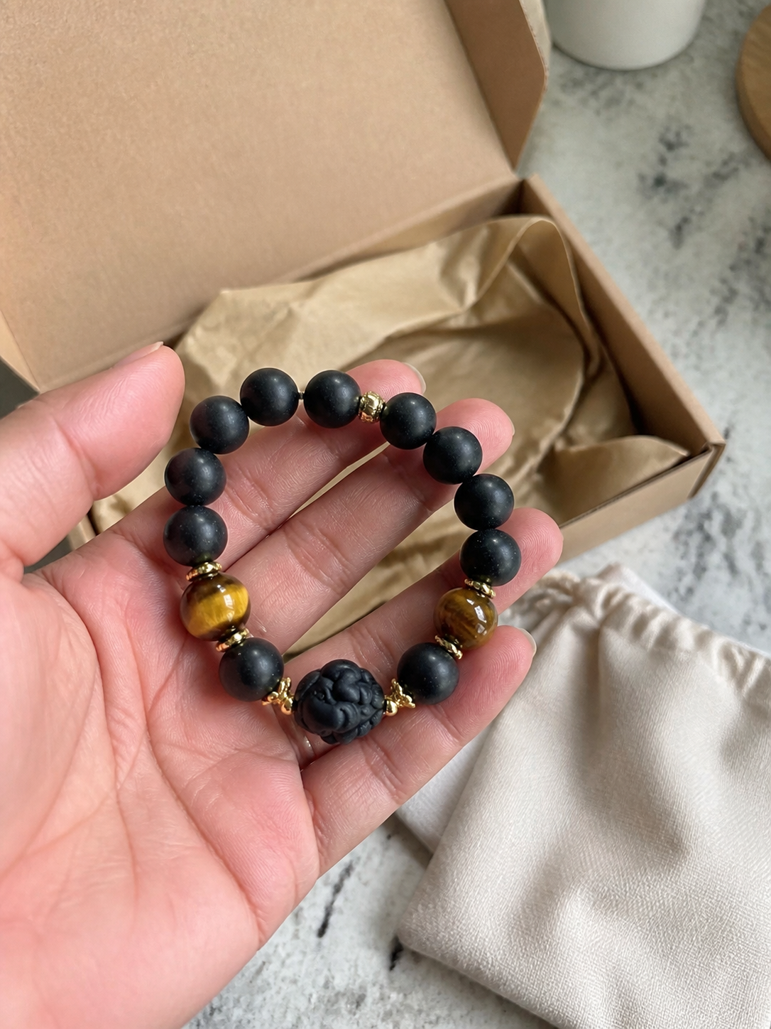Customer unboxing a black incense bracelet with tiger-eye accents